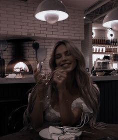 a woman sitting at a table in front of a plate with food and wine glasses