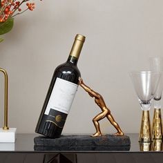 a bottle of wine sitting on top of a table next to two glasses and a vase