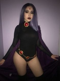 a woman with purple hair wearing a black bodysuit and red beads on her chest