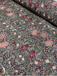 an intricately designed bed sheet with red and green flowers on it