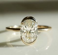 a close up of a diamond ring on a white surface with light shining through it