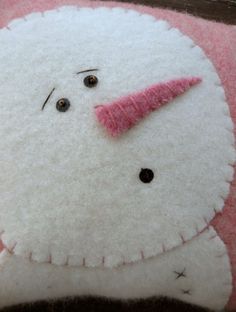 a close up of a stuffed animal made to look like a snowman with pink nose and nose ring