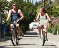 a man and woman riding bikes down the street