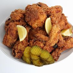 fried chicken with pickles and lemon slices on a white plate, ready to be eaten