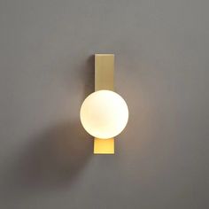 a light that is on the wall next to a gray wall with a white ball