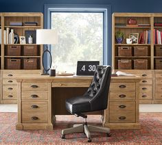 an office with a desk, chair and bookcases in front of a window