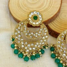 A pair of Golden Wedding Green Chandbali Earring with embedded stones. Size & Other Details Length : 7cm Weight : 20gm/pc Material : Alloy, Pearl, Stone Shape : Drop Shape Attire : Lehenga, Salwar Suit, Kurti, Saree, Flared Dress Gold Jeweled Chandbalis In Bollywood Style, Jeweled Chandbalis For Festivals, Bollywood Style Jeweled Chandbalis For Festivals, Traditional Jeweled Chandbalis For Festivals, Chandbali Jeweled Danglers For Festivals, Jeweled Chandbali Danglers For Festivals, Jeweled Chandbali Earrings For Wedding, Traditional Gold Jeweled Chandelier Earrings, Traditional Green Hoop Earrings For Wedding