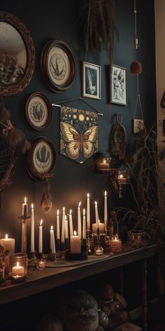 many candles are lit on a table in front of pictures and other things hanging on the wall