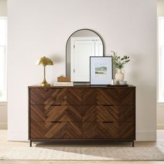 a dresser with a mirror, lamp and pictures on it