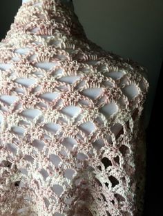 a crocheted shawl is shown on a mannequin