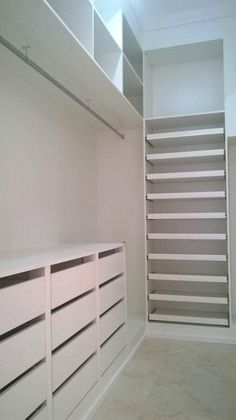 an empty room with white shelves and drawers in it's center area, next to a wall mounted bookcase