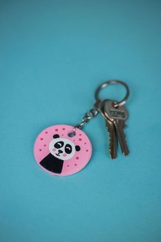 a pink keychain with a panda face on it and a pair of keys