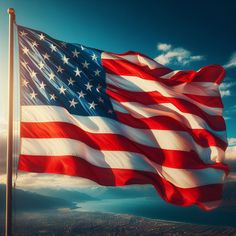 an american flag blowing in the wind on top of a mountain with blue sky and clouds