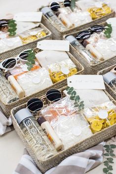 four wicker baskets filled with sunglasses and other items on top of a white table cloth