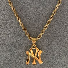 A classic New York pendant design featuring a 3mm luxe rope chain.  Shower, workout or swim - this chain does not tarnish.  Materials: 18K Gold Plated / Stainless Steel Chain Length: 45cm or 50cm Chain Thickness: 3 mm Hypoallergenic / Tarnish-Free Gold Men Jewelry, 90s Gold Jewelry, Yankees Necklace, Gold Jewelry Men, Jewelry Street Style, Ny Necklace, Jewelry Accessories Necklaces, Shower Workout, Gold Necklace Stack