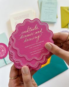 a person holding up a pink card with the words cocktails, dinner and dancing on it