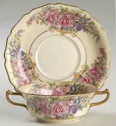 an ornately decorated bowl and saucer with flowers on the rim, sitting next to each other