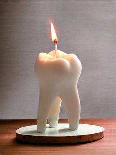 a tooth shaped candle sitting on top of a wooden table