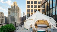 a tent is set up on the roof of a building with city buildings in the background