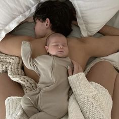 a man and woman laying in bed with a baby sleeping next to eachother