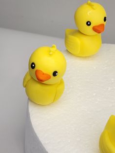 two yellow rubber ducks sitting on top of a white cake