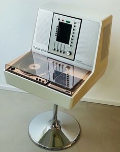 an old fashioned record player sitting on top of a stand in front of a white wall