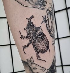 a close up of a person's leg with tattoos on it and an insect