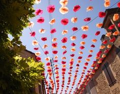 many red and white umbrellas are hanging in the air above a street lined with buildings