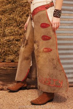 MAKE A STATEMENT IN CHAPS. These mid-Century vintage cowboy working chaps feature red leather accents including waist, tie closures, belt buckles straps, and leather cut out letters reading “DUSTY” sewed at bottom of each leg. Still some life in them left for wearing or would make strong statement décor. hallmarks: leather applique': DUSTY materials: rough out leather, commercial metal findings, leather dimensions: length: 37 1/2" closure: buckle back, tie front vintage condition abrasions and s Vintage Brown Bottoms For Festival, Western Bottoms With Belt Loops For Rodeo, Cowboy Working, Rodeo Chaps, Cowboy Chaps, Leather Applique, Cut Out Letters, Collar Tips, Statement Decor