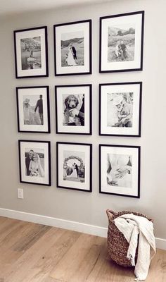 black and white photographs hang on the wall above a laundry basket in a room with wood flooring