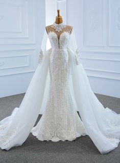 a wedding dress on display in a white room with an open back and long veil