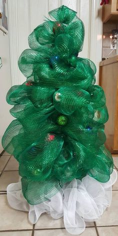 a green christmas tree sitting on top of a tiled floor