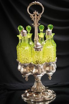 a silver candelabra with three green glass vases sitting on top of it