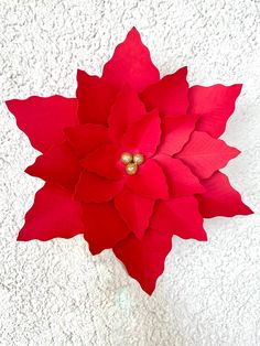 a red poinsettia on a white background with two gold beads in the center