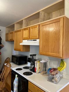 a kitchen with wooden cabinets and white counter tops next to a black stove top oven