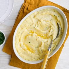 a white bowl filled with mashed potatoes on top of a yellow napkin