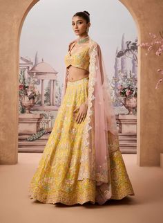 Step into refined elegance with this vibrant yellow lehenga adorned with intricate floral baroque patterns. Embellished with resham, gotapatti, and shimmering sequins, each detail reflects timeless craftsmanship. Paired with a striking pink dupatta, this ensemble offers a harmonious blend of tradition and modern charm, perfect for the sophisticated woman. Semi-stitched Yellow Palazzo Set With Floral Embroidery, Yellow Palazzo Set With Intricate Embroidery For Diwali, Yellow Palazzo Set With Sheer Dupatta For Wedding, Yellow Mirror Work Sets For Reception, Yellow Embroidered Palazzo Set For Diwali, Yellow Floral Embroidered Palazzo Set For Festivals, Yellow Sets With Mirror Work For Reception, Yellow Palazzo Set With Dupatta For Reception, Yellow Gota Work Sets For Reception