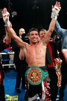 a man with his arms in the air holding up two boxing gloves and standing next to each other