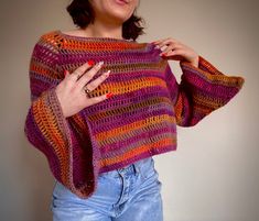 a woman wearing a multicolored knitted sweater and holding her hands on her hips