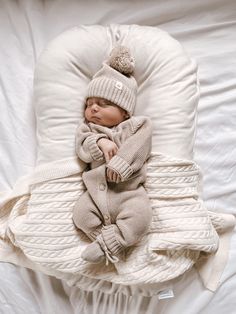 a newborn baby wrapped in a blanket and wearing a knitted hat sleeping on a beanie