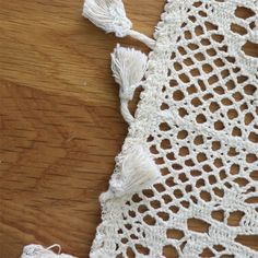 a piece of crocheted white fabric with tassels on top of it