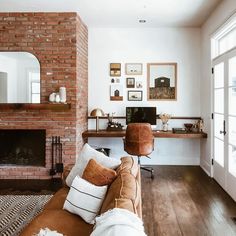 a living room filled with furniture and a fire place in front of a brick fireplace