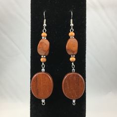 These long dangle earrings are made of oval flat medium brown wood, and oval twist medium brown wooden bead with silver hematite accents. They are almost 3 1/2 inches long and they have a surgical steel hook. Clear rubber earring backings included. Cheap Brown Earrings With Dangling Beads, Handmade Oval Brown Earrings, Brown Teardrop Wood Jewelry, Brown Wooden Beads Oval Jewelry, Brown Wooden Oval Beads Jewelry, Brown Jewelry With Oval Wooden Beads, Brown Wooden Dangle Jewelry, Elegant Brown Wooden Jewelry, Twist Medium