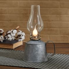 an old fashioned oil lamp is sitting on a table next to a pile of cotton