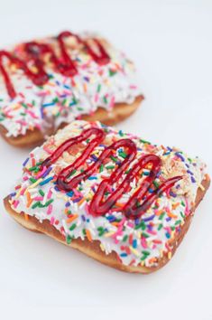 two donuts with white frosting and sprinkles on them are sitting side by side