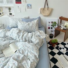 a bed covered in blue and white sheets next to a black and white checkered floor