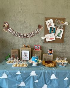 a blue table topped with lots of desserts next to a wall covered in pictures