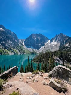 the sun shines brightly over a mountain lake surrounded by pine trees and rocky terrain