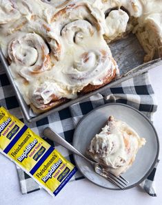 a pan filled with cinnamon rolls on top of a table next to a piece of cake