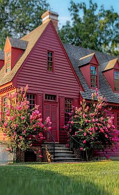 a red house with pink flowers in the front yard